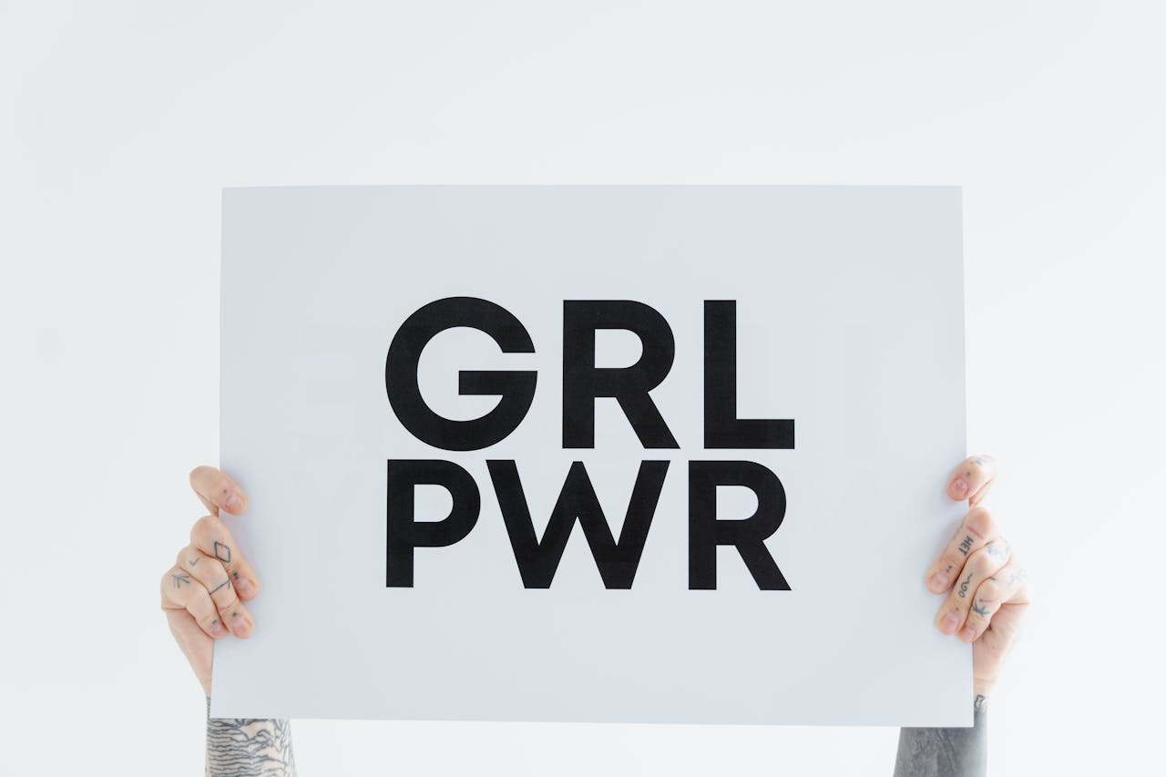Hands holding a 'GRL PWR' sign against a white background, symbolizing empowerment.
